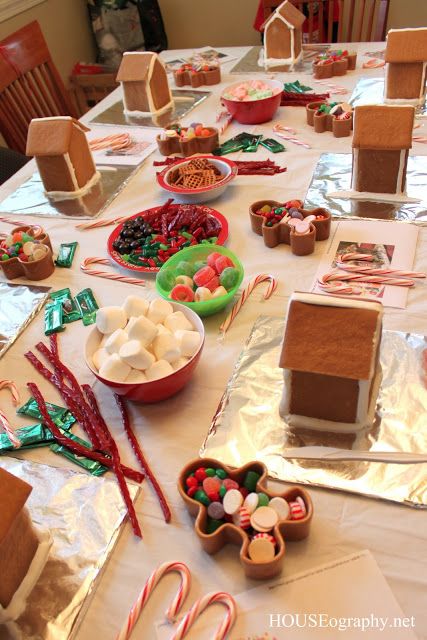 the table is covered with gingerbread houses, candy bars and candies for christmas