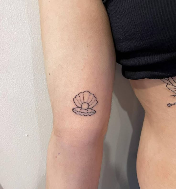 two women with tattoos on their arms, one has a shell and the other has a flower