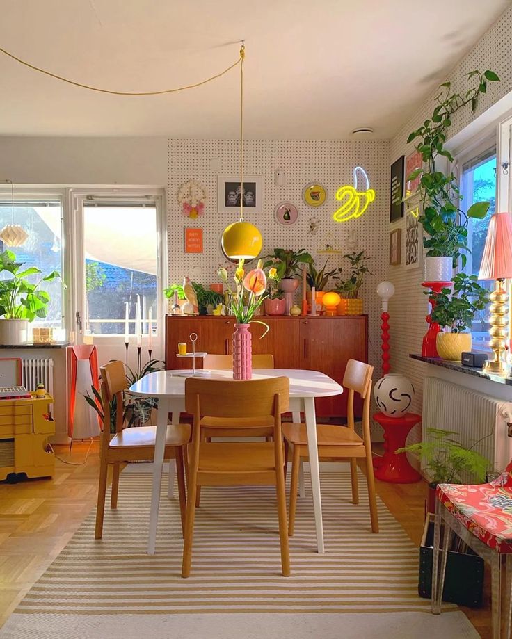 a dining room table and chairs with plants on the windowsills in front of them