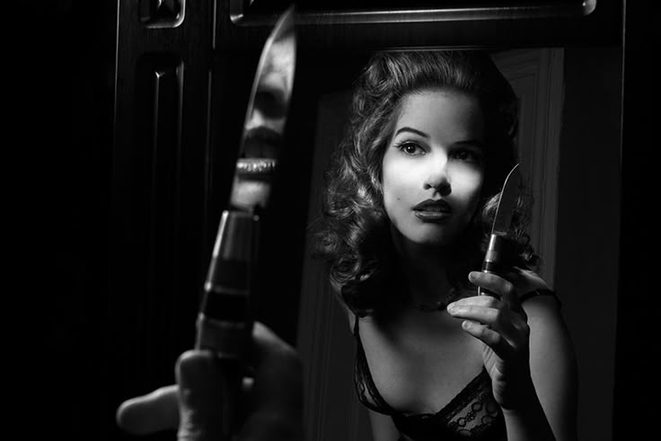 a woman is holding a knife and looking in the mirror