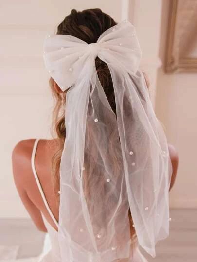 the back of a woman wearing a white veil with pearls on it's head