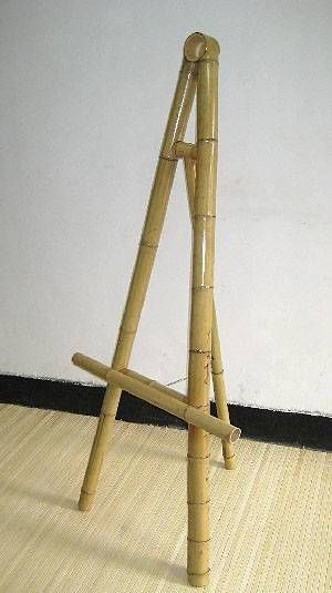 a small wooden easel sitting on top of a floor next to a white wall