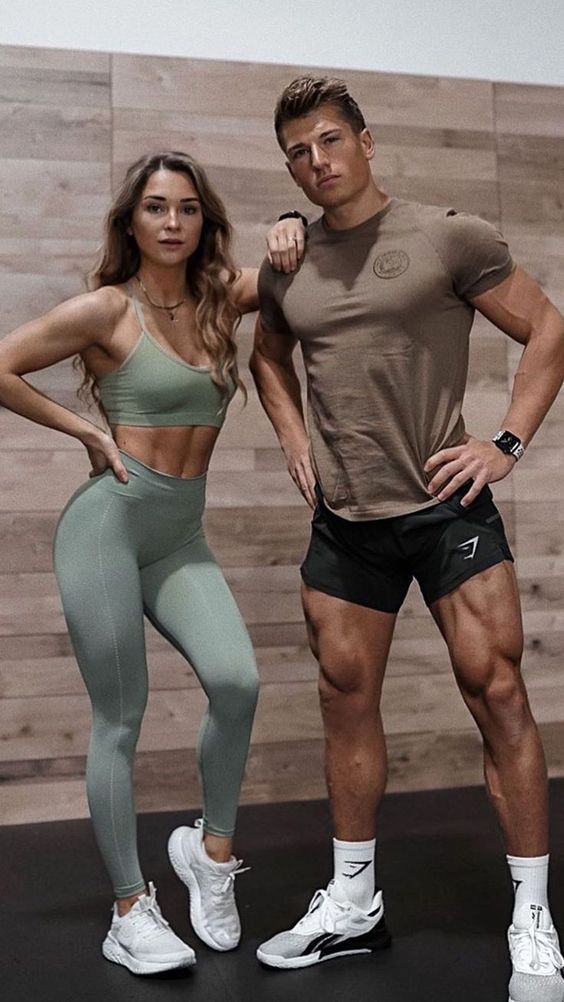 the man and woman are posing together in their gym clothes, one is showing off his muscles