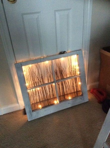 an old window is decorated with lights and reeds for the winter season to brighten up