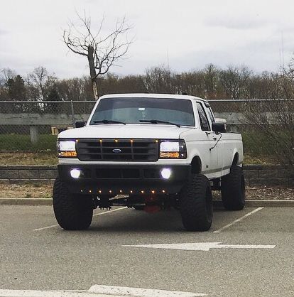 a white pickup truck parked in a parking lot next to a fenced area with trees