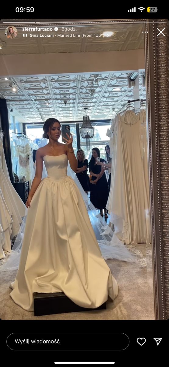 a woman is taking a selfie in front of wedding gowns on mannequins