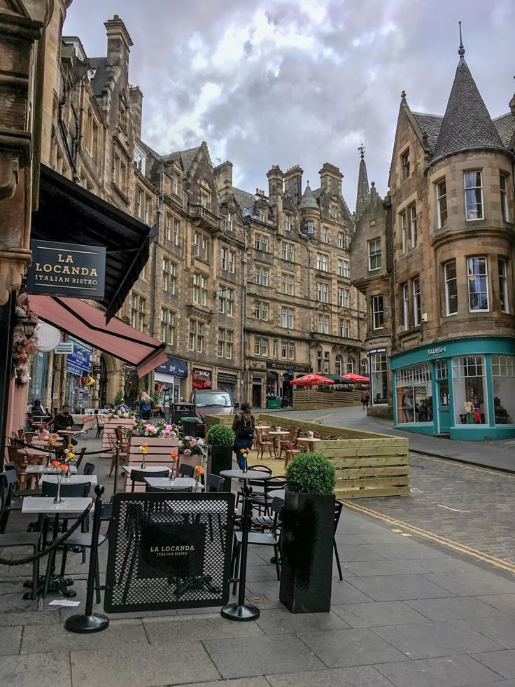 tables and chairs are set up outside in front of the old buildings on an overcast day