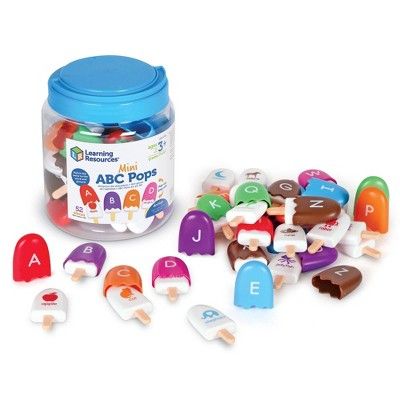 a jar filled with lots of colorful plastic letters next to a pile of small toys