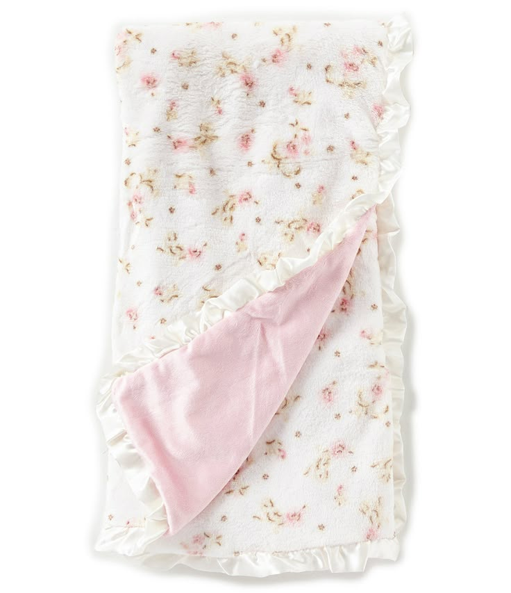 a blanket with pink flowers on it and a white ruffle around the edge is folded up