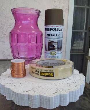 a pink vase sitting on top of a table next to some tins and other items