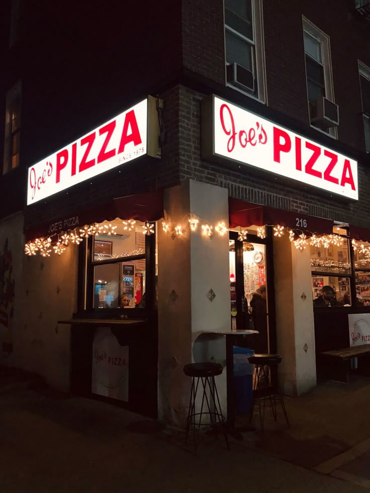 the front of a pizza shop at night