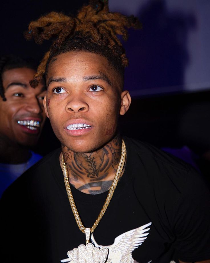 a man with dreadlocks on his head is looking at the camera while wearing a black t - shirt