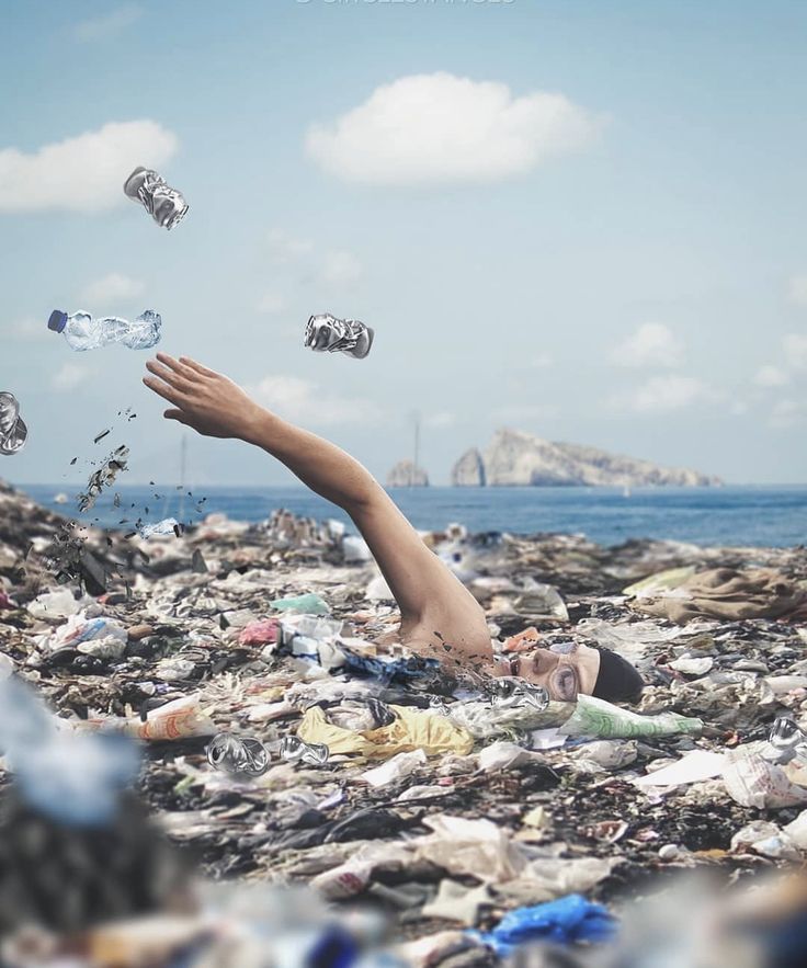 a person laying on top of a pile of trash next to the ocean with plastic bottles floating in the air