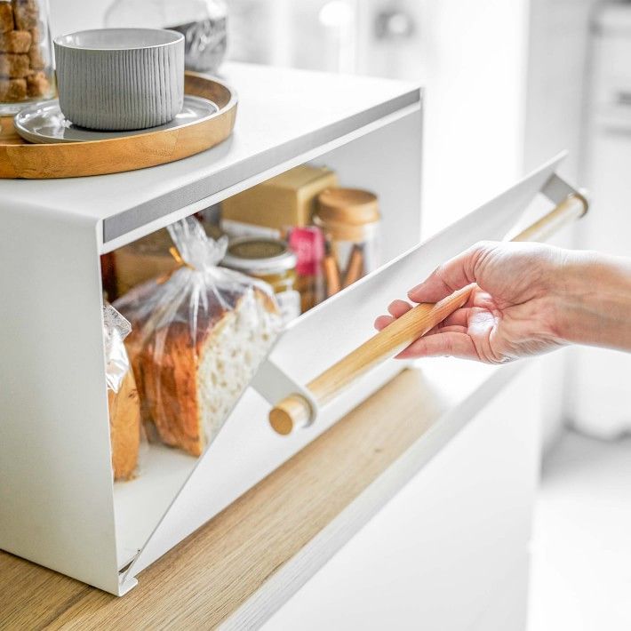 a person holding a piece of wood in front of a microwave door with bread on it