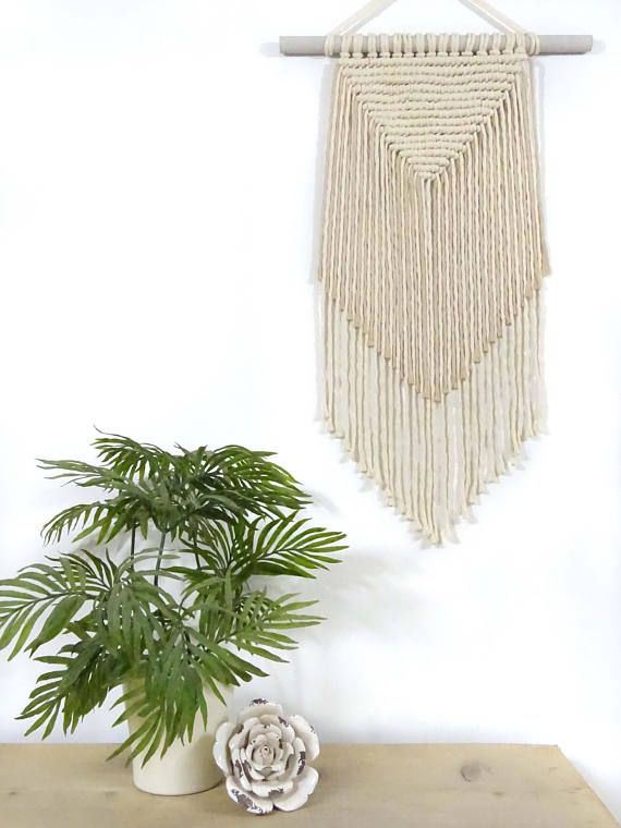 a potted plant sitting on top of a wooden table next to a macrame wall hanging