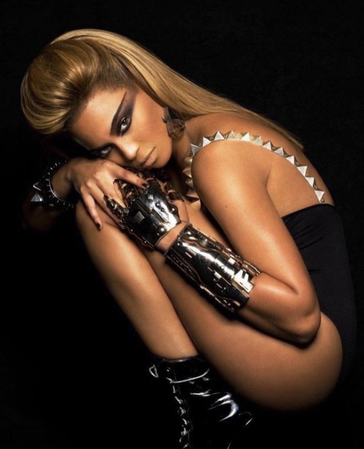 a woman in black and white is posing with her hands on her face while wearing silver gloves