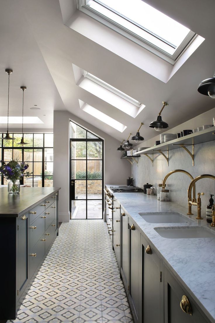 a kitchen with skylights and white countertops on both sides of the room is shown