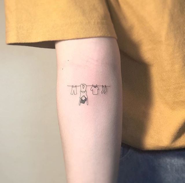 a person with a tattoo on their arm that has three clothes hanging from the line