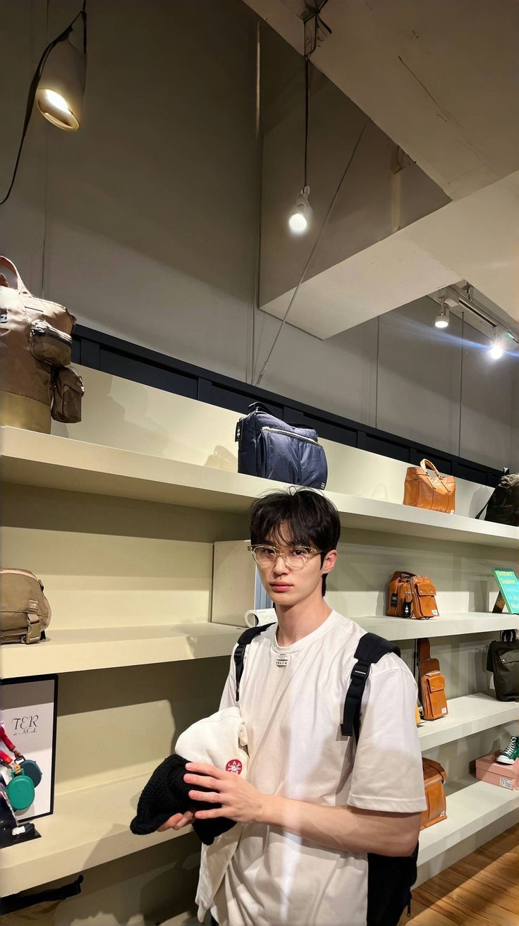 a young man is standing in front of shelves with handbags