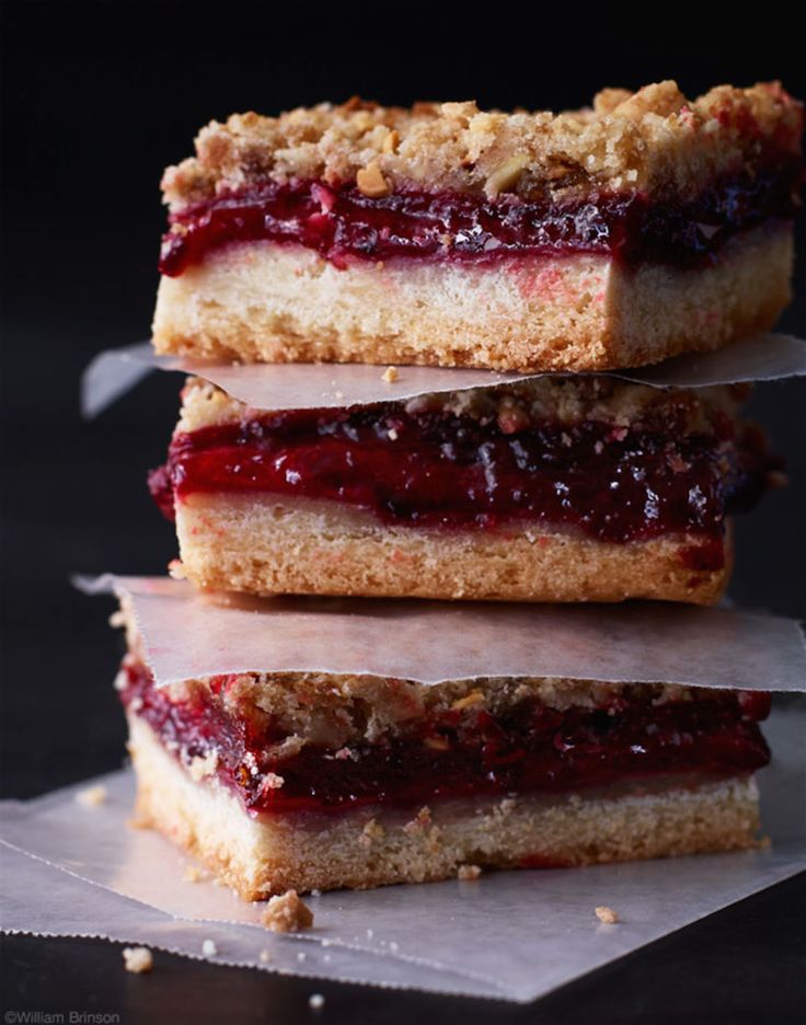 three dessert bars stacked on top of each other with cranberry sauce in the middle