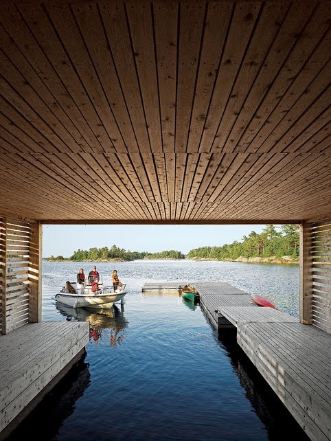 several people are on a boat in the water under a wooden structure that is connected to a dock