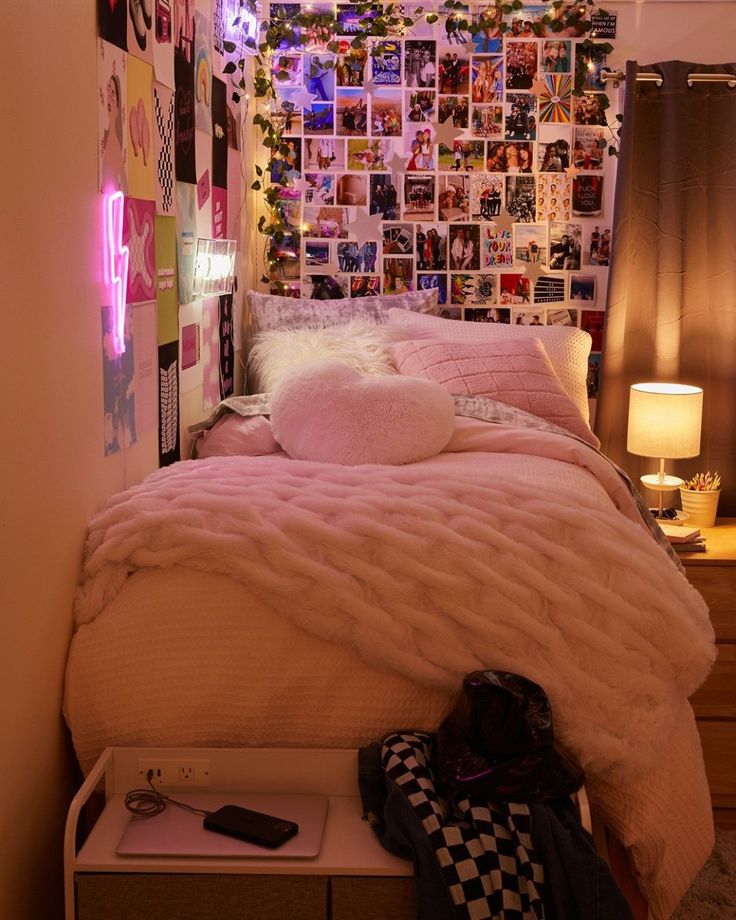 a bed with pink comforter and pillows in a room decorated with pictures on the wall