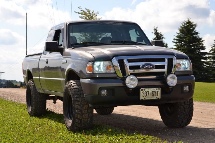 the truck is parked on the side of the road in front of grass and trees