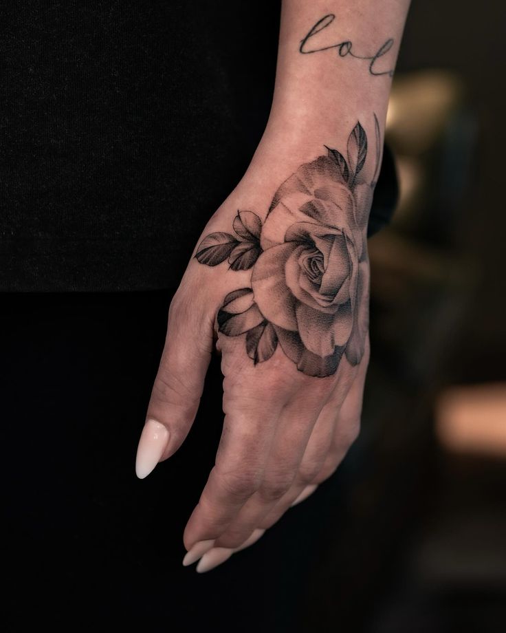 a woman's hand with flowers on it and the word love written in black ink