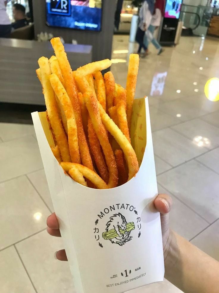 a person holding up a paper bag filled with french fries