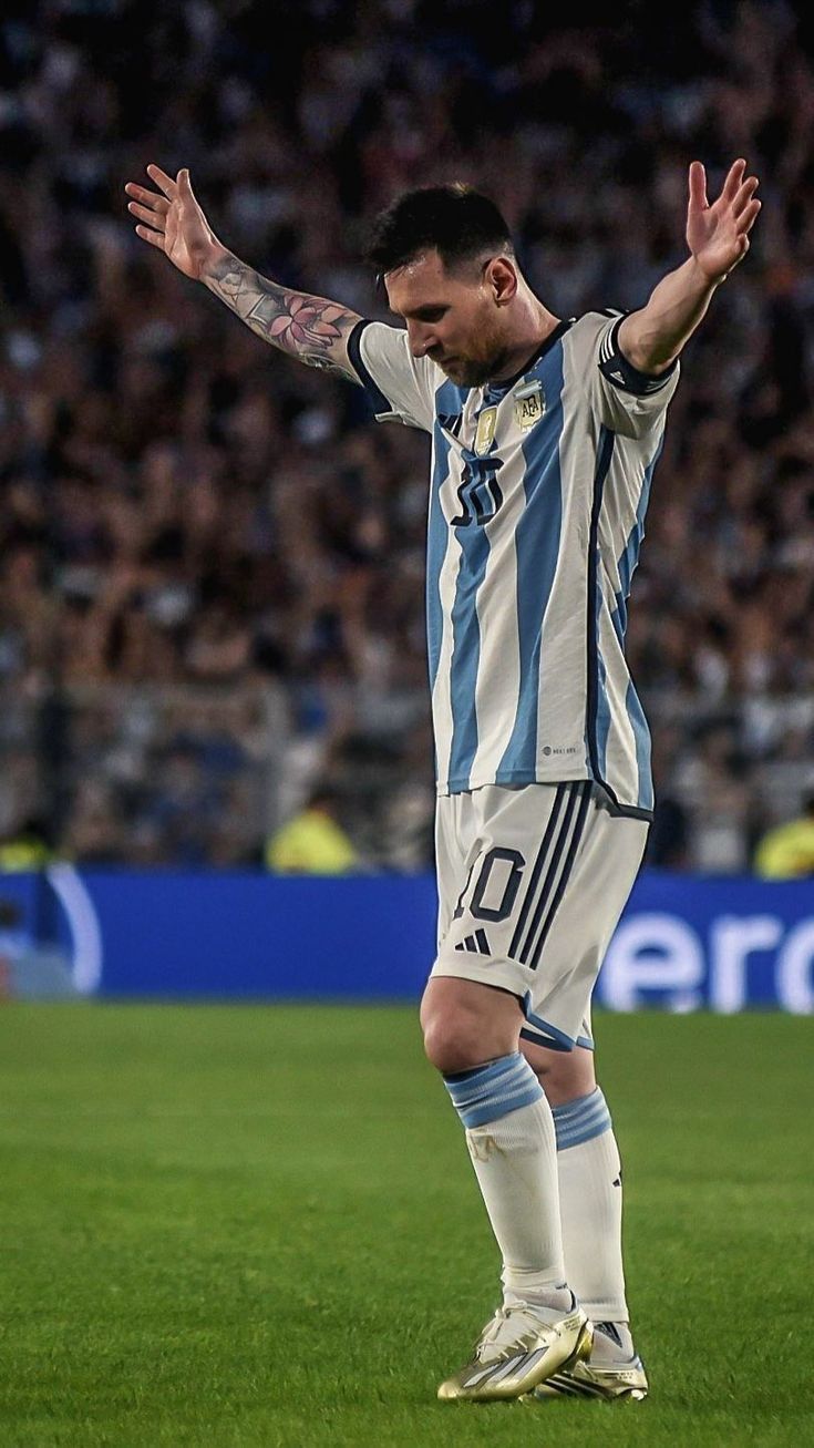 a man standing on top of a soccer field holding his hands up in the air