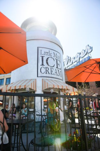 an ice cream shop with orange umbrellas and people