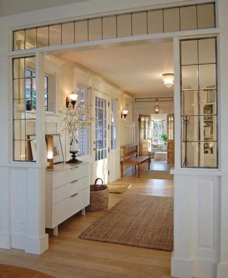 an open door leading into a living room with white furniture and glass doors on both sides