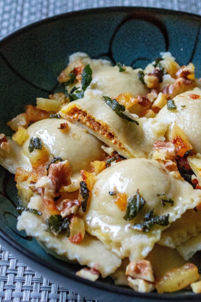 a black plate topped with ravioli covered in cheese