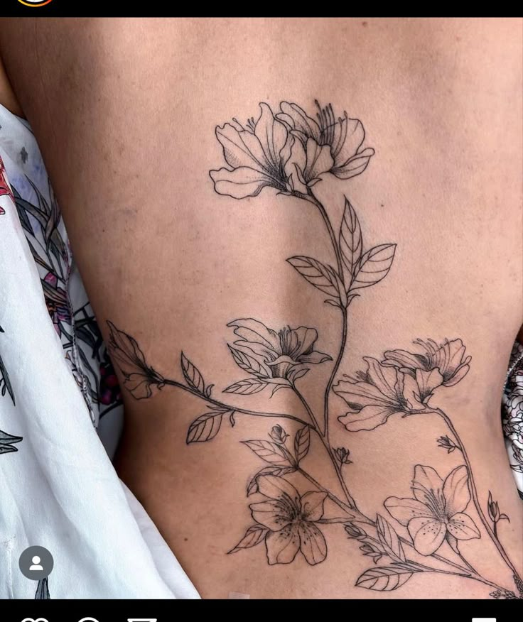 a woman's lower back with flowers on the side and leaves growing out of it