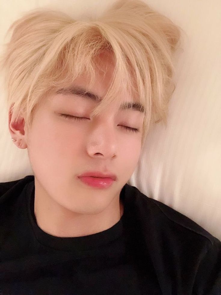 a young man sleeping on top of a bed with his head resting on the pillow