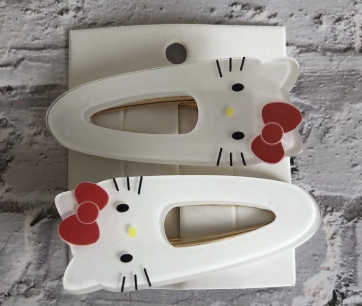 two hello kitty toothbrush holders on a brick wall, one is white and the other is red