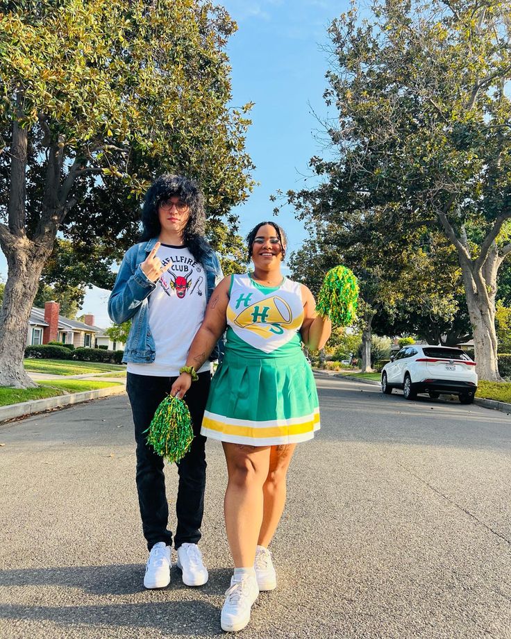 two people standing in the middle of a street holding cheerleader's pom poms