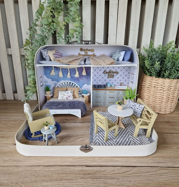 a doll house with furniture and accessories on a wooden table next to a potted plant