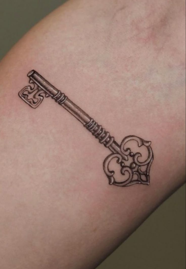 a small key tattoo on the arm