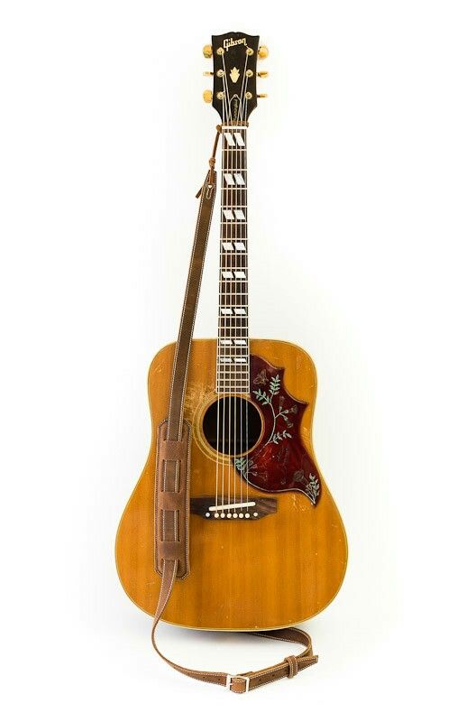 an acoustic guitar is sitting on the ground with its strap around it's neck