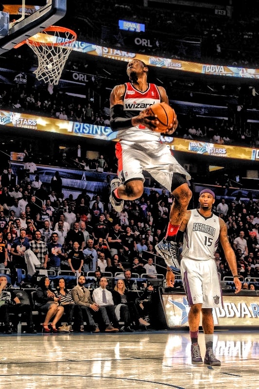 a basketball player jumping up into the air to dunk a ball in front of an audience