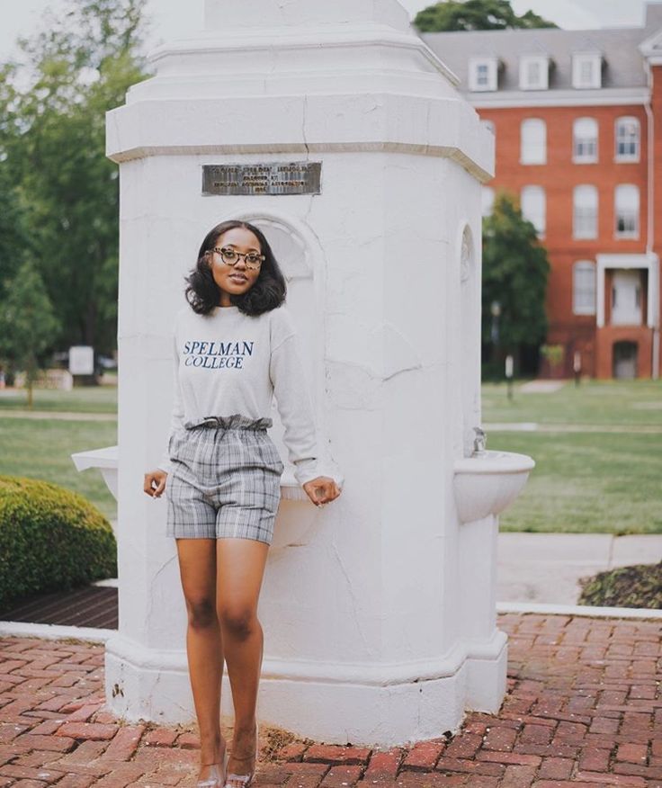 a woman standing in front of a white monument with her hands on her hips and looking at the camera