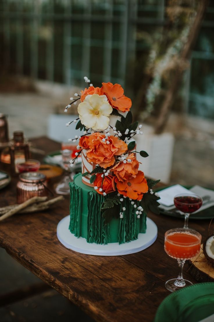 a green and orange cake sitting on top of a wooden table next to wine glasses