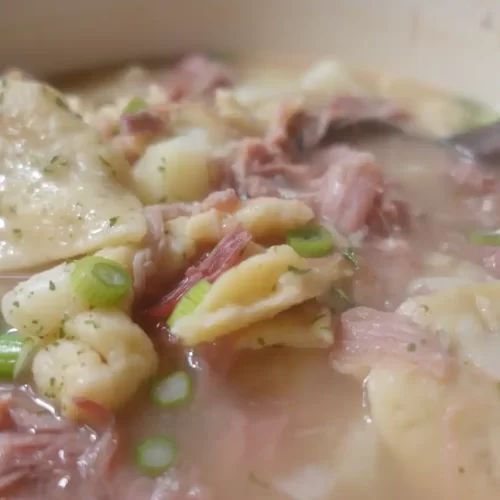 a bowl filled with soup and meat in it's broth, garnished with green onions