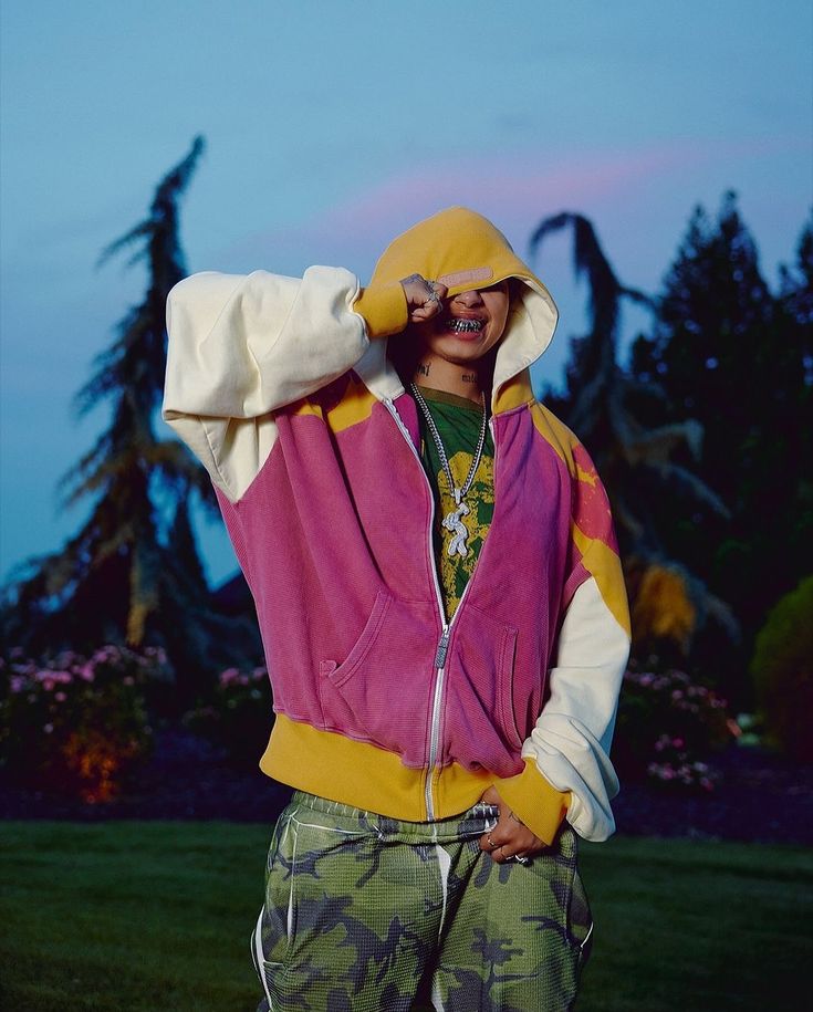 a man in camouflage pants and a hoodie looks through his binoculars at the sky