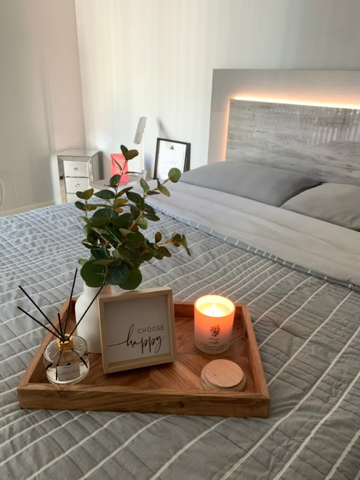 a tray with a candle and some flowers on top of it in front of a bed