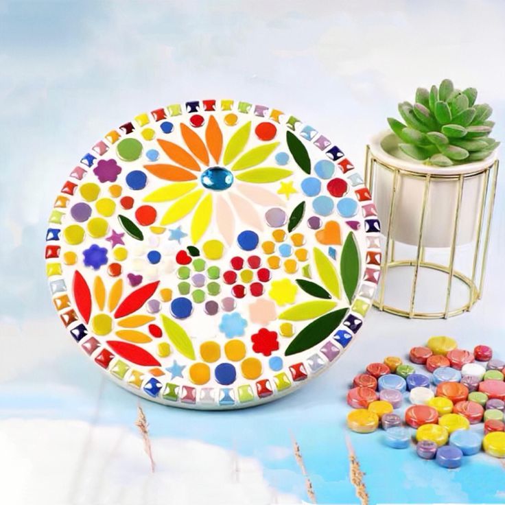 a colorful plate sitting on top of a table next to a potted succulent