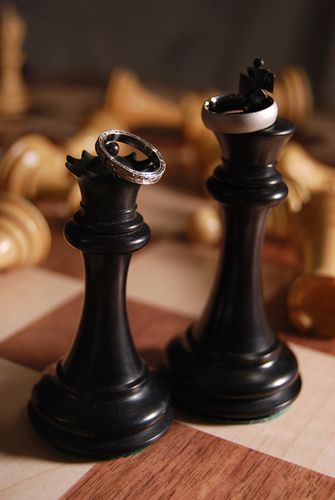 two black chess pieces sitting on top of a checkered board