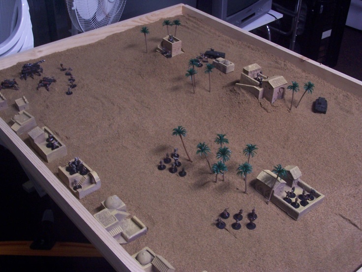 an aerial view of a desert area with palm trees and small buildings on the sand