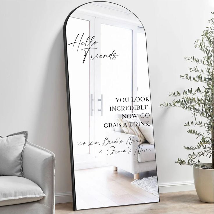 a large mirror sitting on top of a wooden floor next to a chair and potted plant